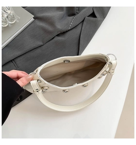 Vue de dessus du sac à bandoulière riveté crème montrant l'intérieur et le fermoir magnétique