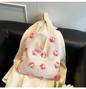 Détail d'un sac en tricot crème avec des fleurs au crochet roses 3D et texture coton