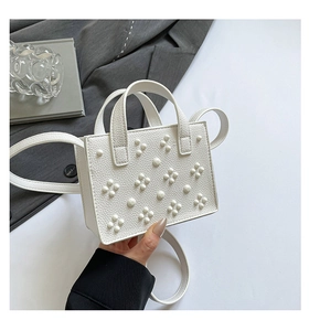 Détail du sac à main blanc orné de clous métalliques et cuir texturé au style élégant