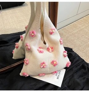 Détail d'un sac cabas en tricot crème avec de délicates appliques florales roses et texture.