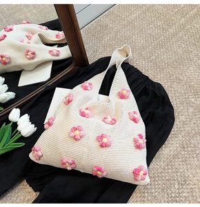 Gros plan d'un sac cabas en tricot beige orné de fleurs 3D roses et jaunes