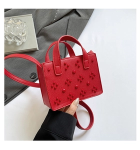 Détail du mini sac rouge en cuir grainé avec rivets fleurs 3D et doubles poignées