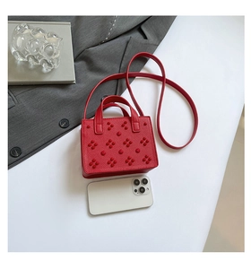Vue détaillée d'un mini sac à main rouge clouté à côté d'un téléphone pour la taille