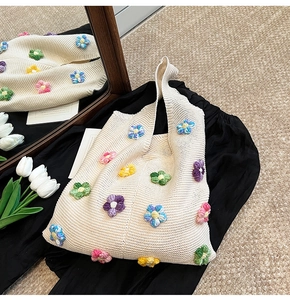 Détail d'un sac cabas en maille beige avec fleurs colorées en crochet 3D et textures