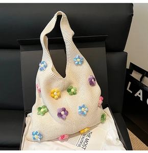 Détail d'un sac cabas en maille beige avec fleurs crochetées 3D dans un coffret cadeau