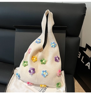 Détail du sac cabas en tricot beige avec fleurs 3D colorées dans une boîte cadeau