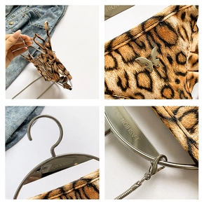 Detailaufnahme von Leopardenmuster-Stoff mit silbernem Schmetterling und Metallkette