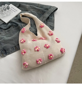 Gros plan sur la texture en tricot et les fleurs en crochet 3D d'un sac à bandoulière crème
