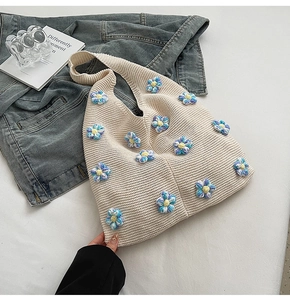 Gros plan détaillé d'un sac cabas en tricot crème avec des fleurs 3D bleues et violettes