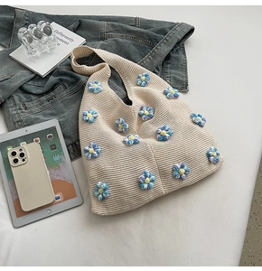 Détail d'un sac à bandoulière en tricot beige avec petites fleurs 3D bleues et blanches