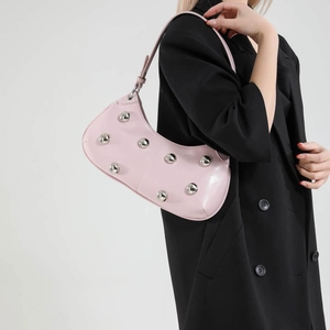 Sac hobo rose brillant avec clous argentés porté par un mannequin en blazer noir