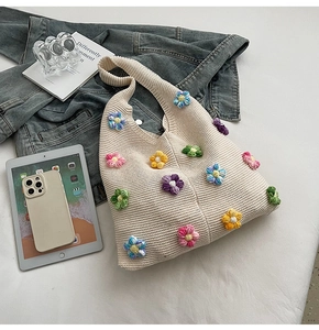 Gros plan d'un sac en tricot crème avec des fleurs au crochet 3D colorées et texture douce