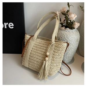 Detailed close-up of beige woven straw tote bag with tassels, beads and fabric lining
