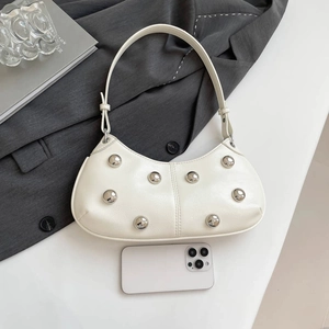 Sac hobo blanc à rivets argentés en cuir texturé dans un décor minimaliste moderne