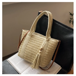 Detailed close-up of woven cream straw bag with wood bead tassels and leather shoulder strap