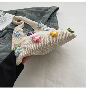 Détail d'un sac bandoulière en tricot beige avec des fleurs colorées en relief 3D