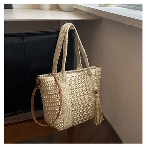 Detail of hand-woven straw tote bag with wood bead tassels and leather shoulder strap