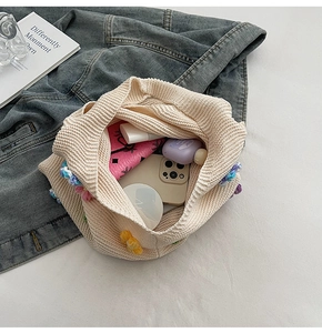 Vue intérieure du sac en maille beige avec fleurs colorées, téléphone et maquillage