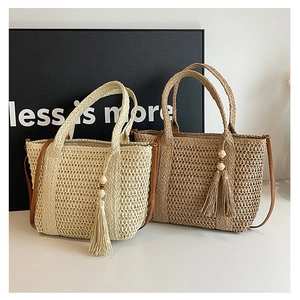 Close-up of woven straw bags with large fringe tassels and wooden bead details