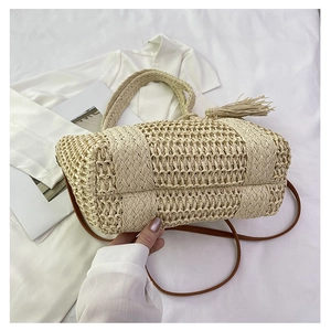 Close-up of beige woven straw handbag showing fine craftsmanship and tassel detail