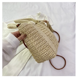Close-up of woven straw bag detail featuring hollow knit pattern and brown fringe tassel