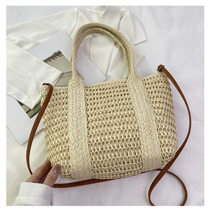 Detailed close-up of beige woven straw tote bag with brown leather handles and textures