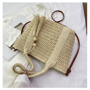 Detail of woven straw shoulder bag with wooden beads tassel and leather straps