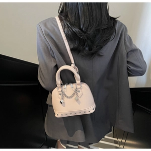 Vista posteriore della modella con borsa a tracolla rosa a conchiglia con borchie