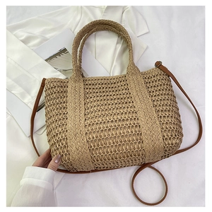 Detail of hand-woven straw beach bag with intricate hollow mesh pattern and leather strap