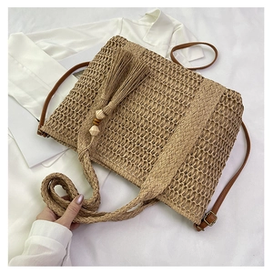 Detail of straw woven beach bag with tassel, wooden beads and brown leather strap