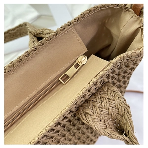 Close-up of the woven straw tote bag featuring a secure zipper closure and fabric lining