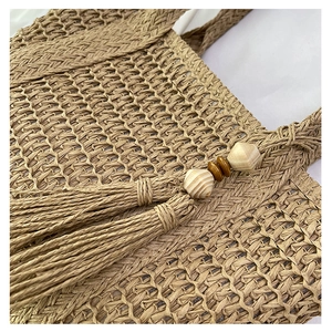 Detail of hand-woven straw tote with elegant tassel and wooden bead decoration