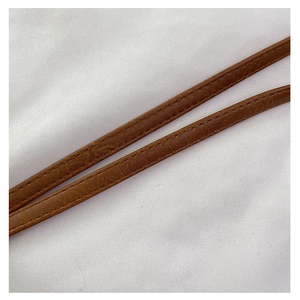 Macro view of brown leather handle with fine stitching on minimalist woven beach bag