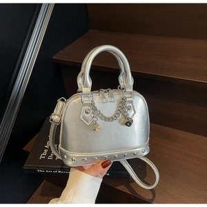 Dettaglio borsa a conchiglia argento con borchie metalliche e pendente a dado decorativo