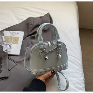 Dettaglio mini borsa azzurra con catena d'argento, ciondolo a dado e borchie metalliche