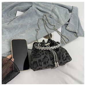 Detail of leopard print bucket bag with crystal trim and silver chain on denim background