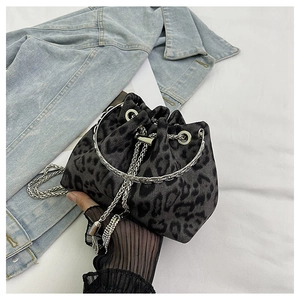 Detail view of mini leopard print bucket bag with silver metal handle and chain strap