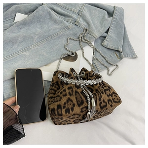 Detailed shot of leopard print bucket bag with rhinestone chain and silver strap over denim