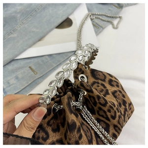 Detail of leopard print bucket bag featuring a crystal handle and silver chain strap