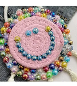 Detail of hand-woven pink and white round bag with iridescent bead smiley face and tassel