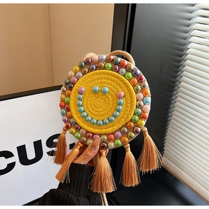 Detailed view of hand-woven round straw bag with beaded smiley face and tassels