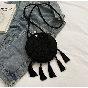 Detail of black round woven crossbody bag with long tassels and bohemian cord strap