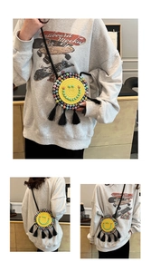 Detail of yellow woven round crossbody bag featuring a green beaded smiley face and tassels