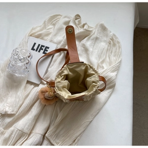 Détails du sac bandoulière en paille avec lanière en cuir, pompon et fermoir magnétique
