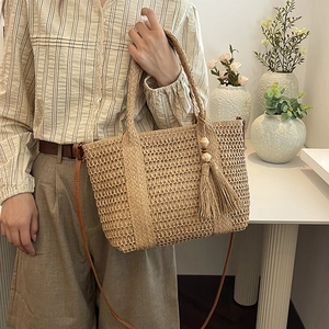 Beige woven straw beach bag with tassels, wooden beads and brown leather strap
