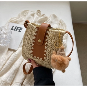 Détail du sac en paille avec bandoulière en cuir brun, franges et breloque ours en peluche