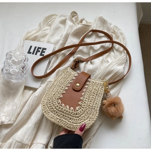 Détail du sac bandoulière en paille avec rabat en cuir brun et breloque ours en peluche