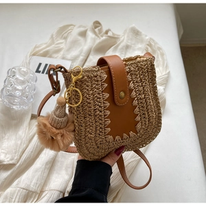 Sac bandoulière minimaliste en paille avec bandoulière en cuir et charm pompon tricoté