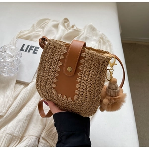 Détail du sac bandoulière en paille tressée avec rabat en cuir et pendentif chapeau