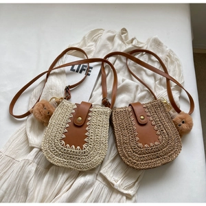 Détail de sacs bandoulière en paille avec rabat en cuir et charmant pendentif chien
